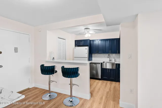 a kitchen with stainless steel appliances kitchen island granite countertop a refrigerator a stove a oven with white cabinets and wooden floor