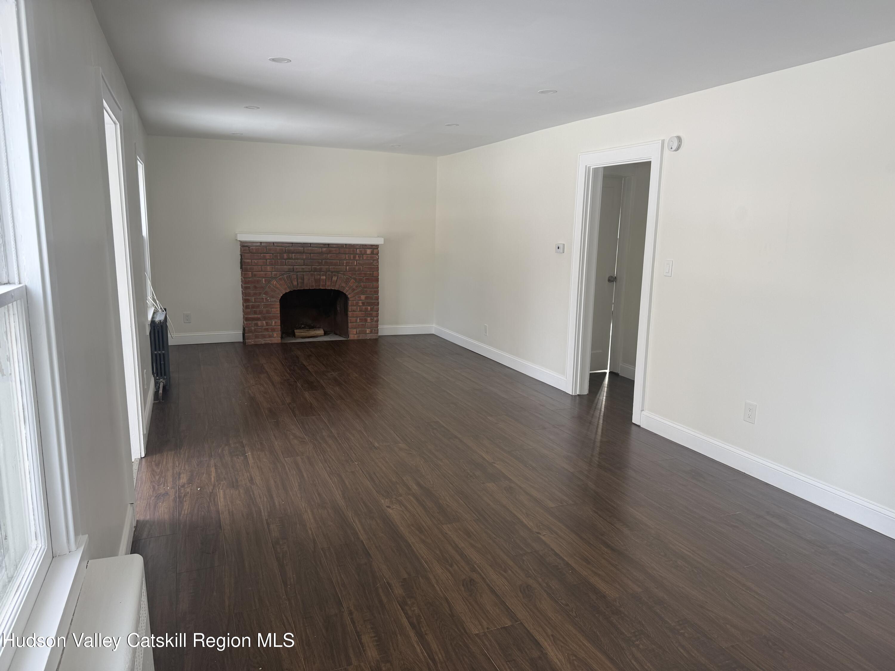 222 Zandhoek Road Hurley, NY 12443 - Photo 4 of 23 an empty room with wooden floor and fireplace