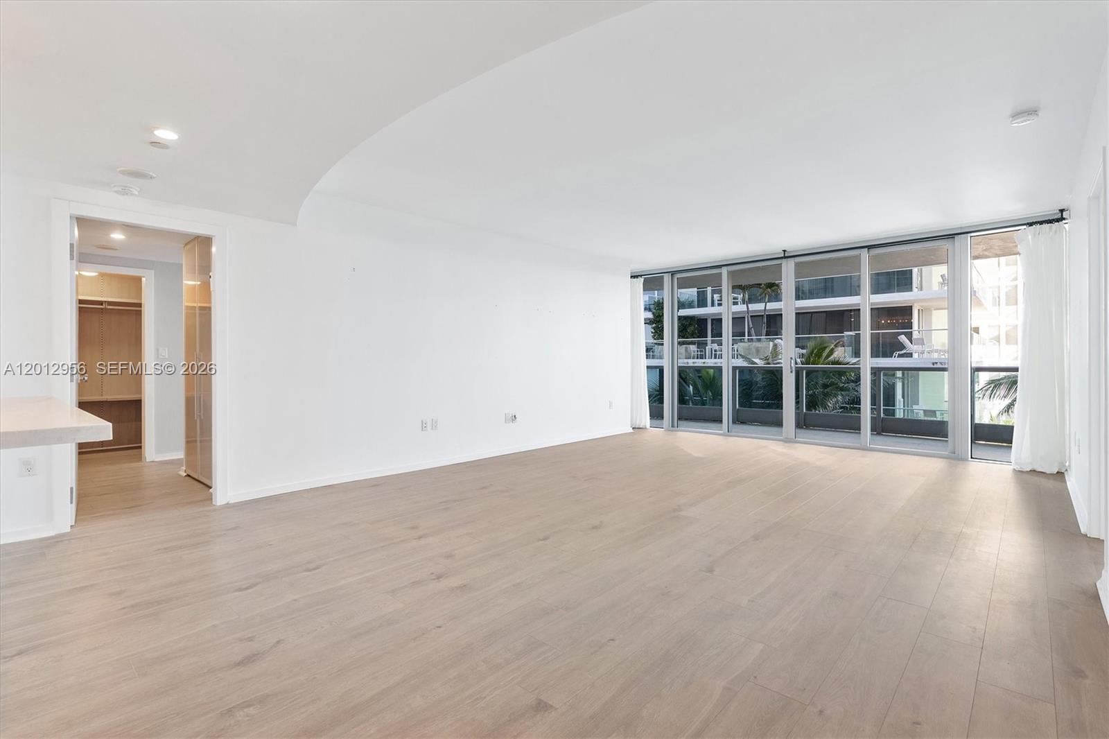 9401 Collins Avenue, Unit 505 Surfside, FL 33154 - Photo 5 of 39 an empty room with wooden floor and windows