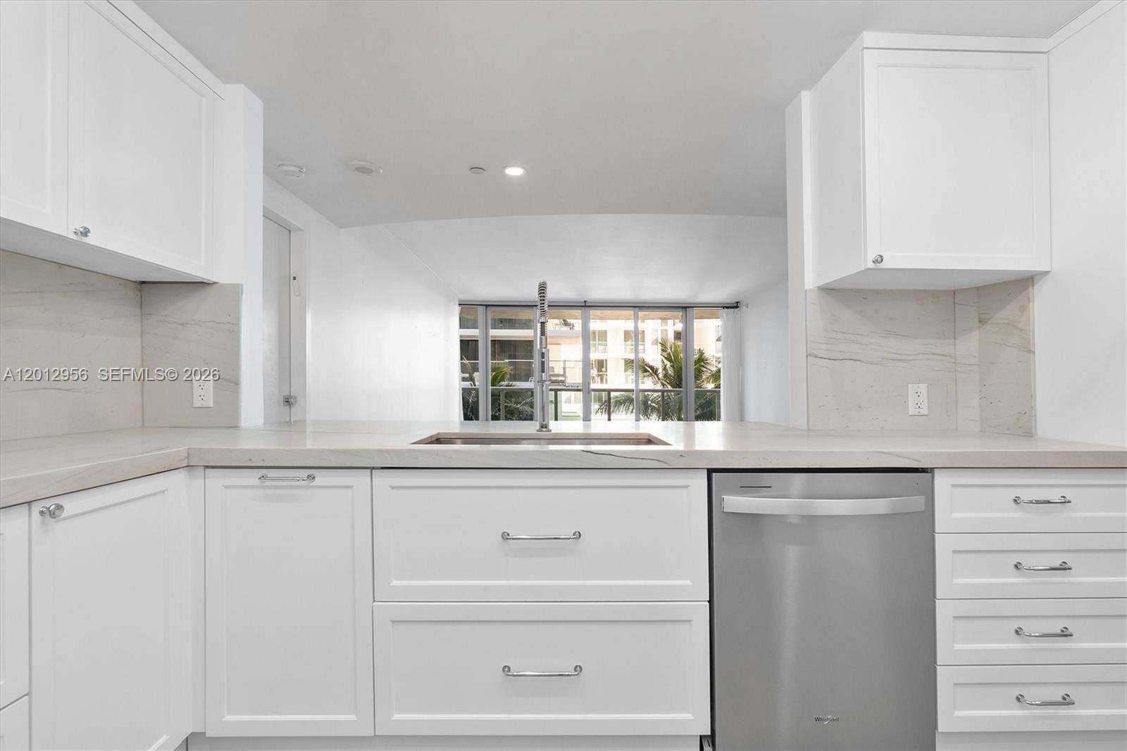 9401 Collins Avenue, Unit 505 Surfside, FL 33154 - Photo 9 of 39 a kitchen with granite countertop white cabinets and a window