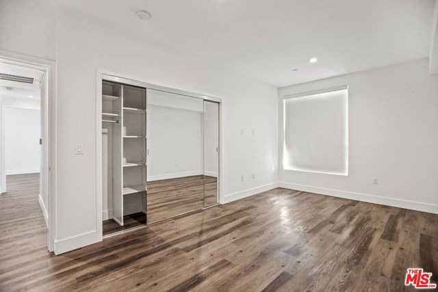 a view of an empty room with wooden floor and closet