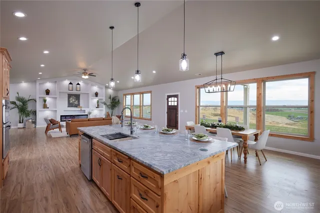 a open kitchen with stainless steel appliances granite countertop a stove top oven a dining table and chairs with wooden floor