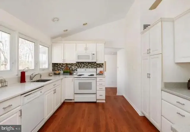 a kitchen with granite countertop white cabinets and white appliances