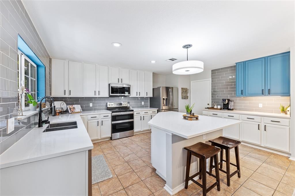 201 South Sumac Lane Georgetown, TX 78633 - Photo 7 of 15 Kitchen featuring appliances with stainless steel finishes, a breakfast bar area, hanging light fixtures, a center island, and white cabinetry