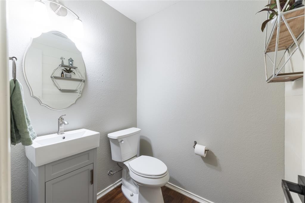201 South Sumac Lane Georgetown, TX 78633 - Photo 8 of 15 Half bath featuring a textured wall, vanity, and dark wood finished floors
