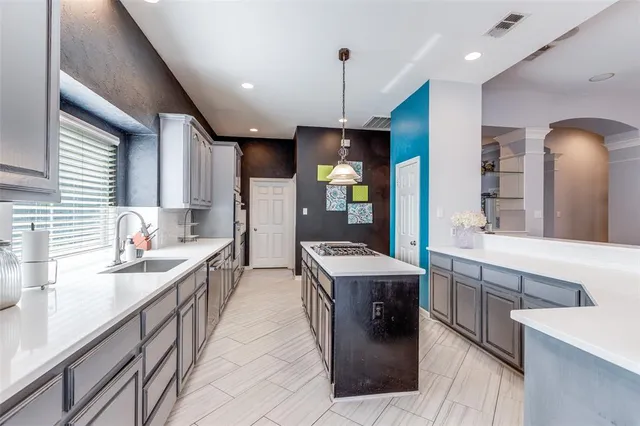 a large kitchen with a large counter top a sink stainless steel appliances and cabinets