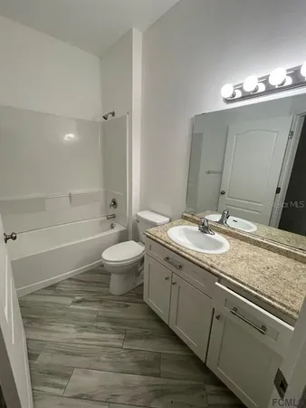 a bathroom with a granite countertop sink a toilet and a large mirror