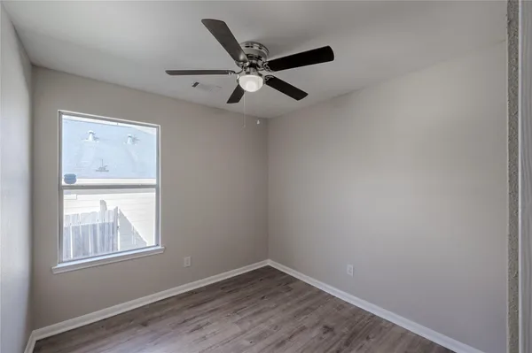 an empty room with windows and fan