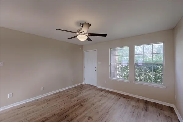 an empty room with wooden floor and windows