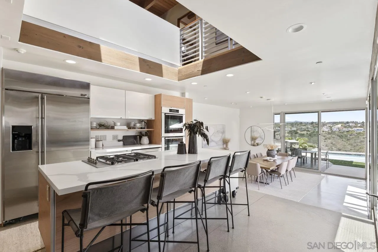 1635 Gascony Road Encinitas, CA 92024 - Photo 19 of 41 a kitchen with stainless steel appliances kitchen island granite countertop a table chairs stove and refrigerator