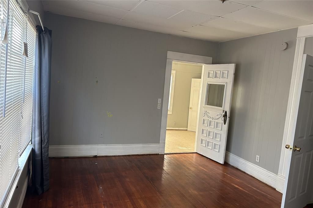 701 South Clements Street Gainesville, TX 76240 - Photo 19 of 28 an empty room with wooden floor and windows