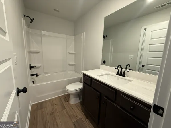 a bathroom with a sink a toilet a mirror a bathtub and shower