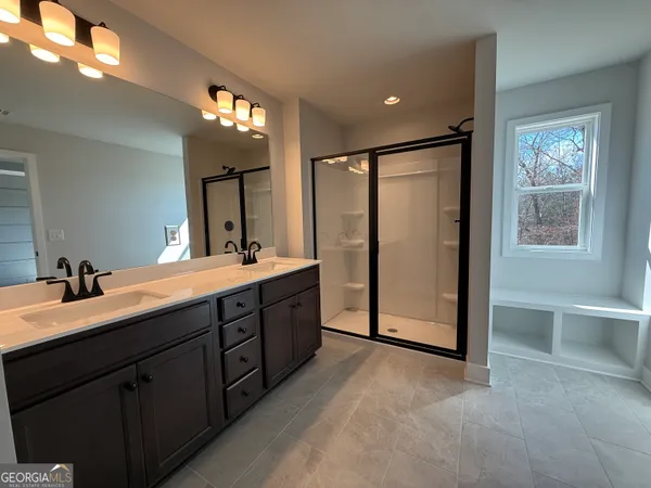 a spacious bathroom with a double vanity sink a mirror and a shower