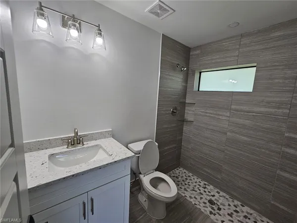a bathroom with a granite countertop toilet a sink and mirror