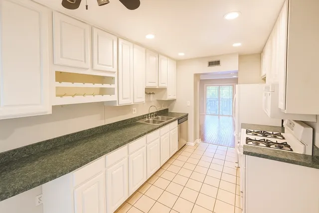 a large white kitchen with granite countertop a sink and a stove