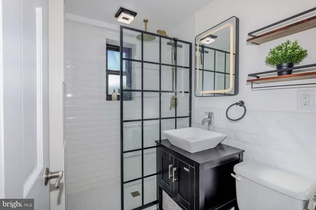 a bathroom with a granite countertop sink a toilet and shower