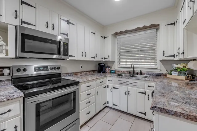 a kitchen with granite countertop a stove sink and microwave