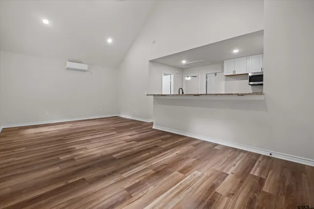 a view of kitchen and empty room with wooden floor