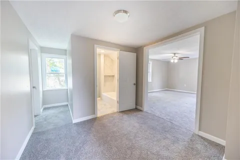 an empty room with windows and chandelier fan