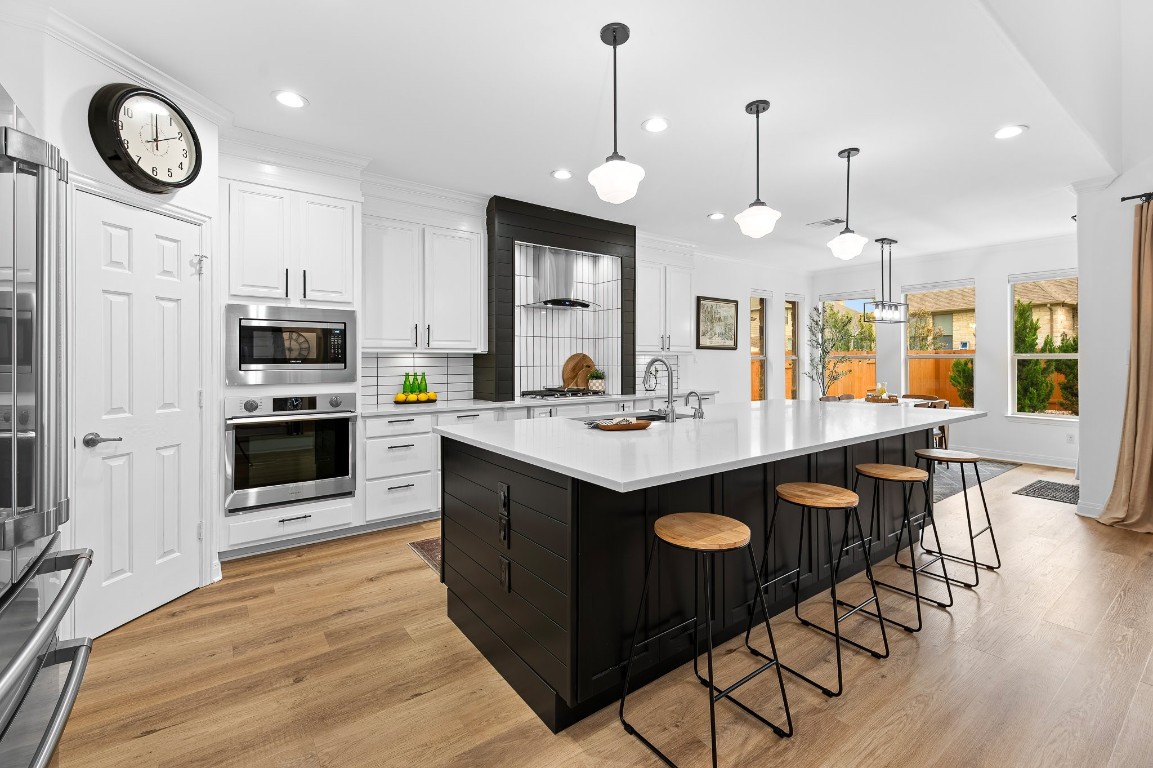 a kitchen with granite countertop a stove a sink dishwasher and a dining table with wooden floor