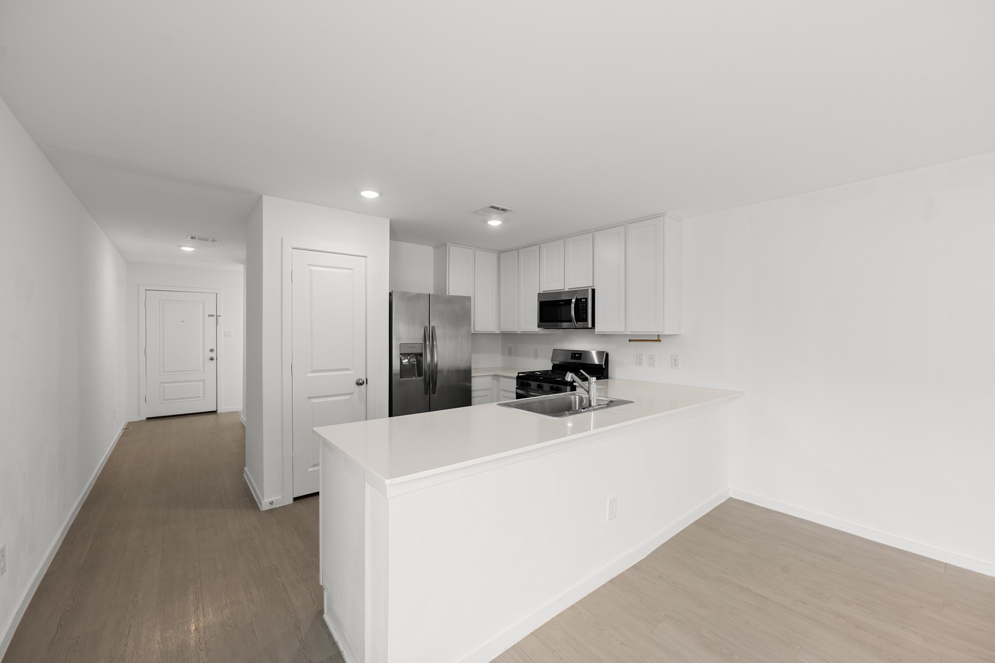 252 Houston Street Angleton, TX 77515 - Photo 4 of 49 A wide peninsula opens the kitchen to the adjoining dining area, creating an easy flow for everyday meals and entertaining. Light-toned flooring and neutral finishes carry throughout the space.