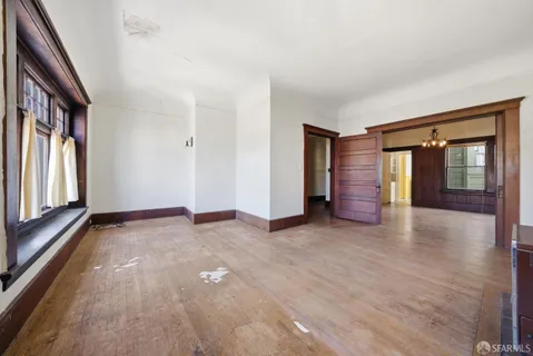a view of an empty room with window and wooden floor