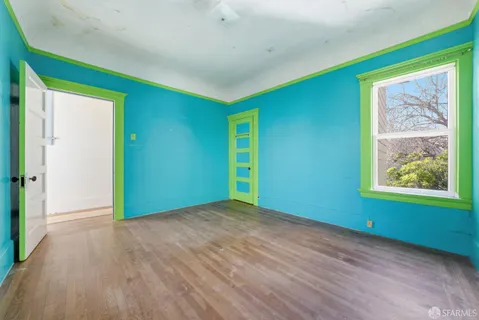 a view of an empty room with window and wooden floor