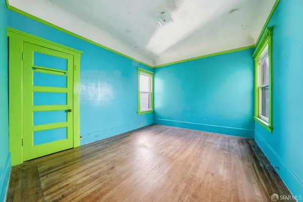 a view of empty room with wooden floor and fan