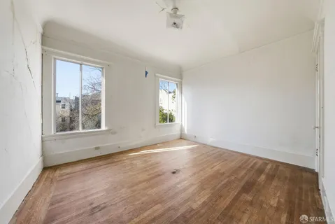 an empty room with wooden floor and windows