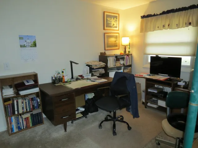 a view of a workspace with furniture and a window