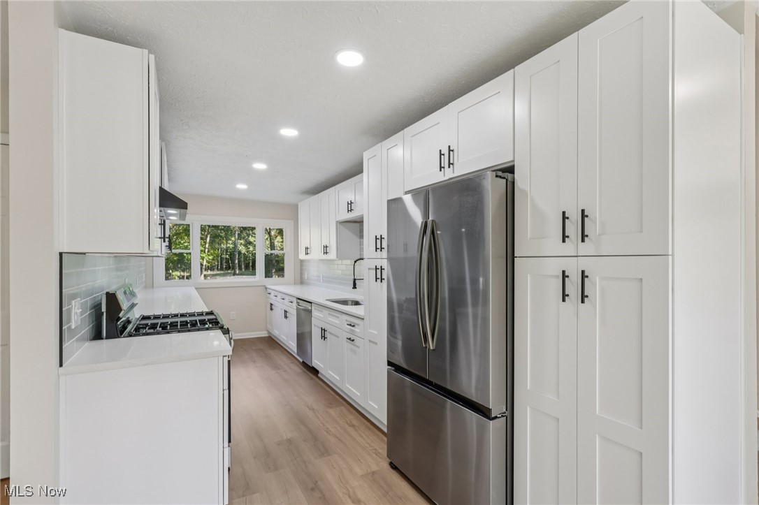 50963 Becker Road Oberlin, OH 44074 - Photo 7 of 37 Kitchen with stainless steel appliances, white cabinetry, light stone counters, recessed lighting, and tasteful backsplash