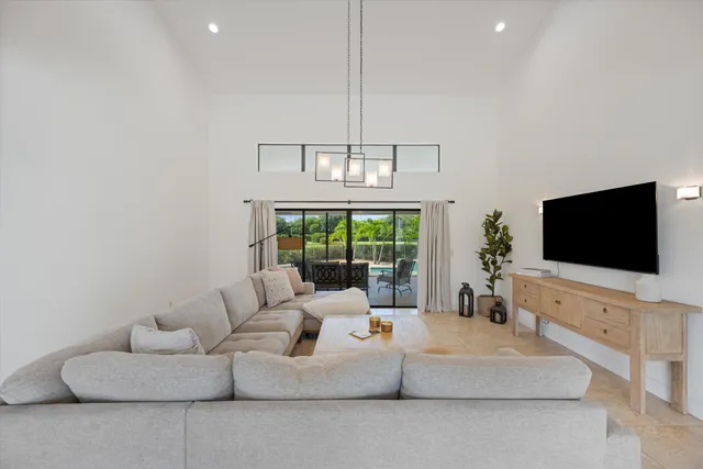 a living room with furniture a flat screen tv and a large window