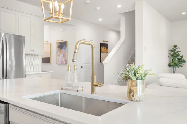 a large white kitchen with stainless steel appliances kitchen island granite countertop a sink and cabinets