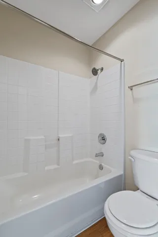 a bath room with a toilet a bath tub and a shower