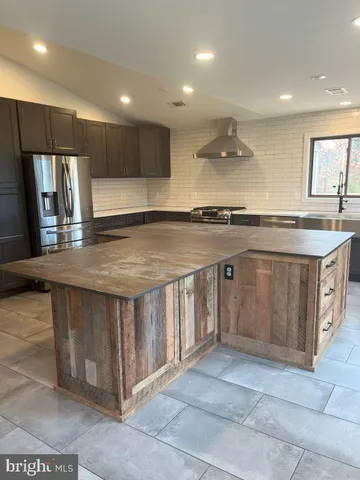 a large kitchen with a large counter top a sink stainless steel appliances and cabinets