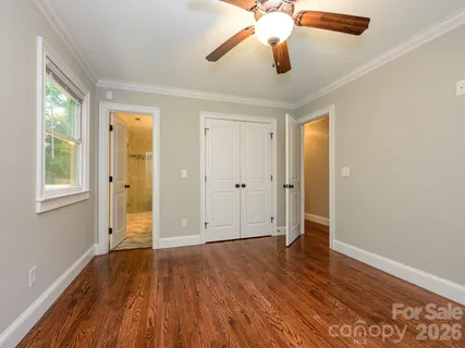 an empty room with wooden floor chandelier fan and windows