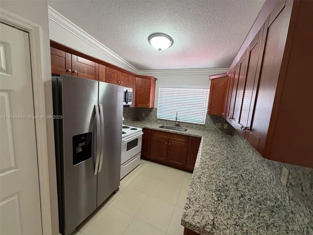 a large kitchen with stainless steel appliances granite countertop a refrigerator and a sink