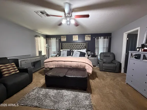a bed room with a bed couches and a flat tv screen