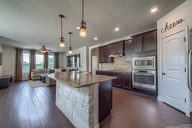 a kitchen with kitchen island a large counter top space appliances and a ceiling fan