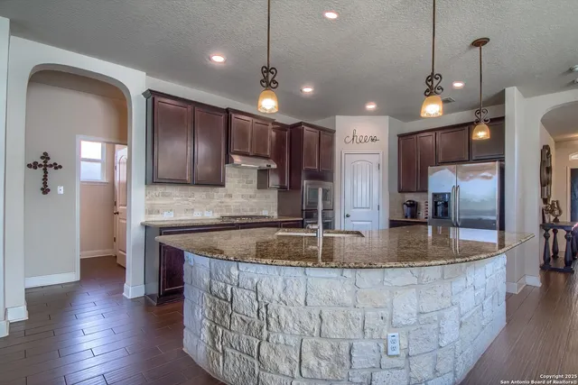 a kitchen with stainless steel appliances granite countertop a sink a refrigerator and a stove
