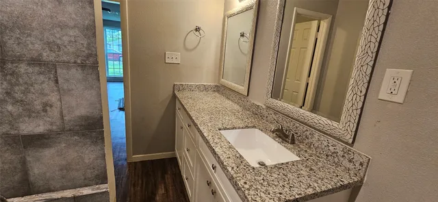 a bathroom with a granite countertop shower a sink and a mirror