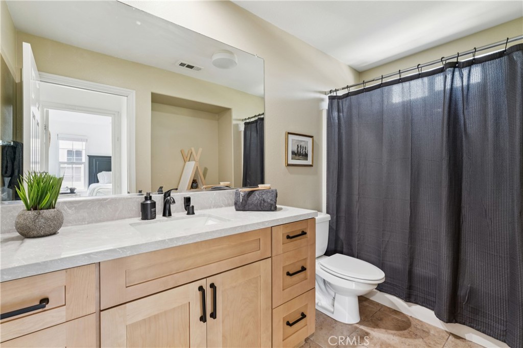 4155 Windspring Street Corona, CA 92883 - Photo 28 of 38 a bathroom with a granite countertop sink a toilet a mirror and shower curtain