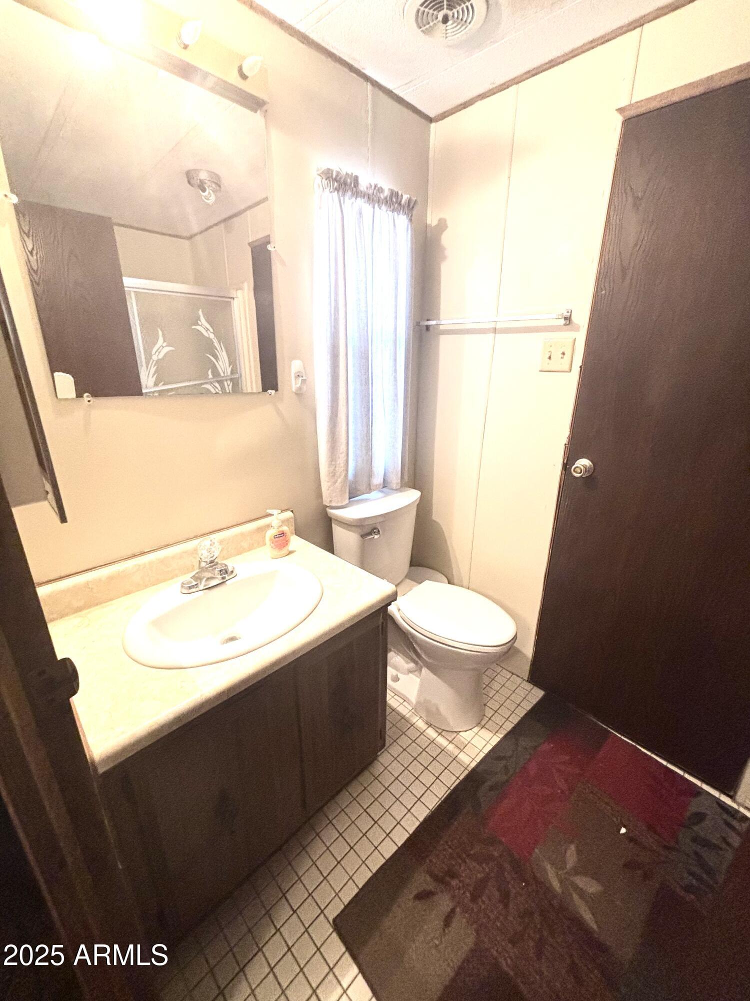 1221 West Nelson Road Ajo, AZ 85321 - Photo 12 of 17 a bathroom with a sink a toilet a mirror and vanity