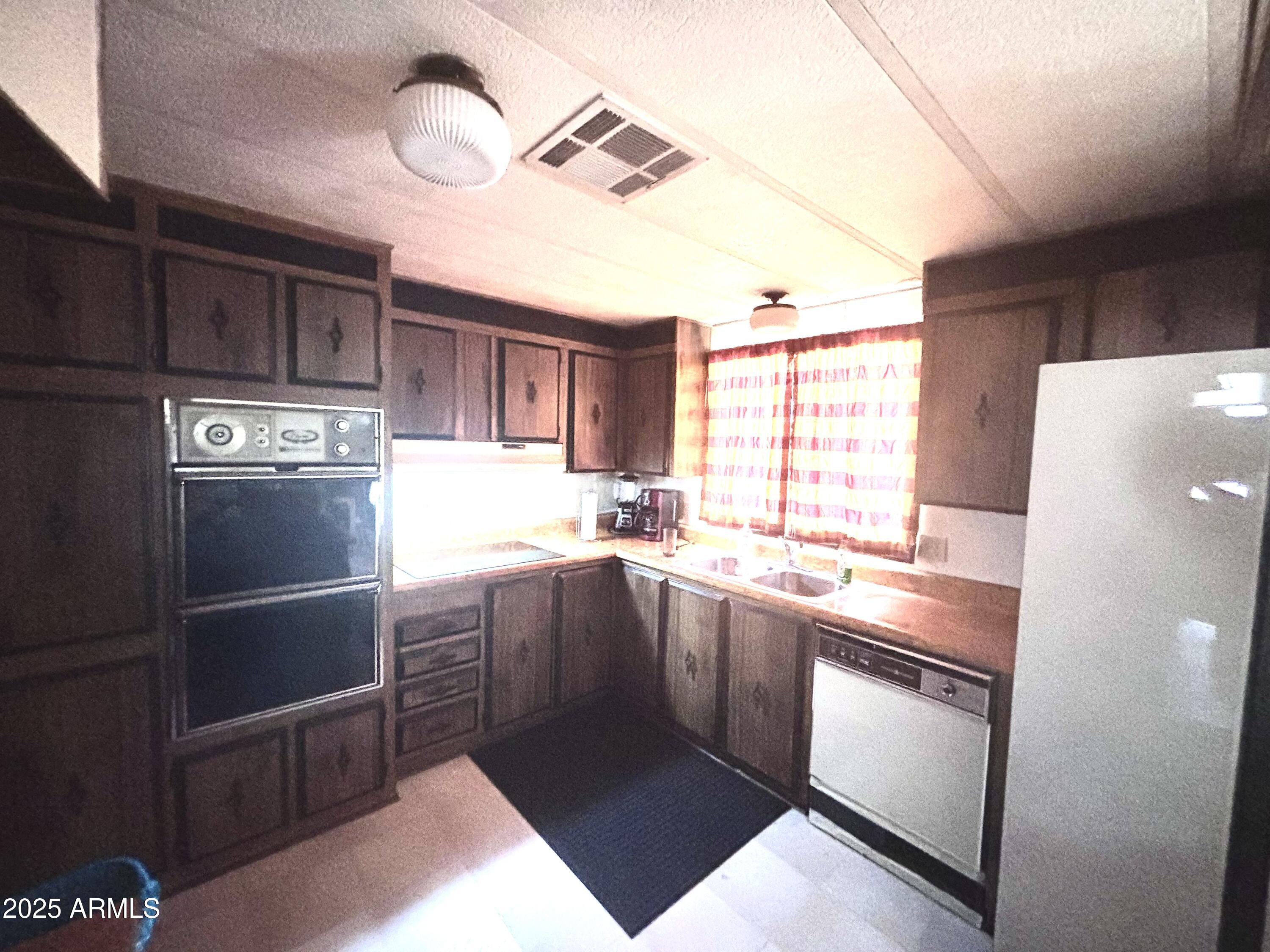 1221 West Nelson Road Ajo, AZ 85321 - Photo 10 of 17 a kitchen with stainless steel appliances granite countertop a refrigerator a sink dishwasher a stove and white countertops with wooden floor