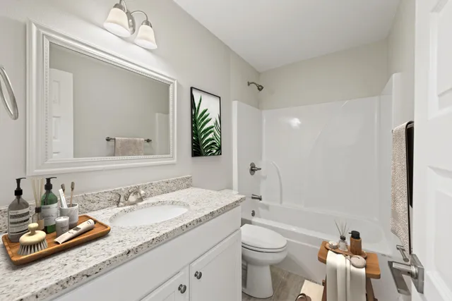 a bathroom with a granite countertop sink mirror vanity and toilet