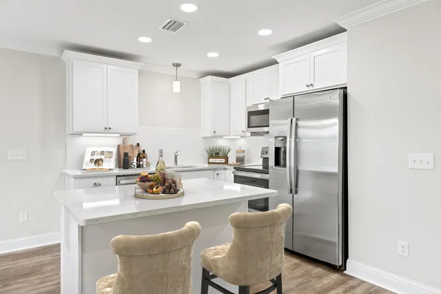 a kitchen with stainless steel appliances a refrigerator a stove a sink and white cabinets