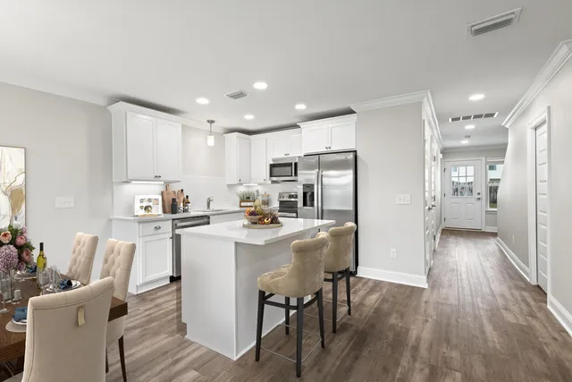 a living room with stainless steel appliances a dining table wooden floor and a window