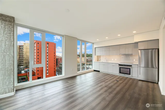 a view of a kitchen with a refrigerator a stove top oven and a wooden floor