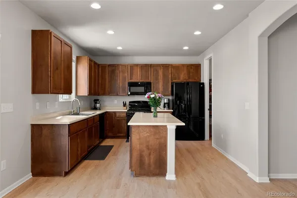a kitchen with kitchen island granite countertop wooden floors stainless steel appliances a sink and a window