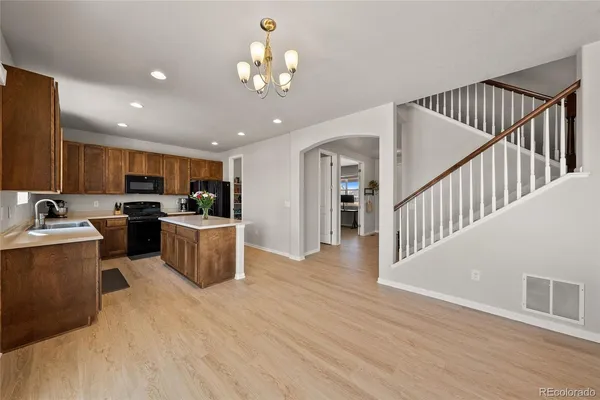 a kitchen with stainless steel appliances kitchen island granite countertop a refrigerator a stove a sink and dishwasher with wooden floor